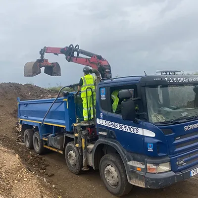 A blue dump truck driving down a dirt road.