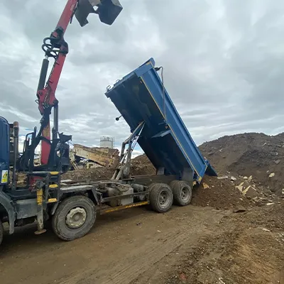 A dump truck is dumping dirt on a dirt road.