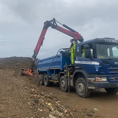 A blue dump truck driving down a dirt road.