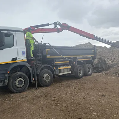 A man standing on the back of a dump truck.