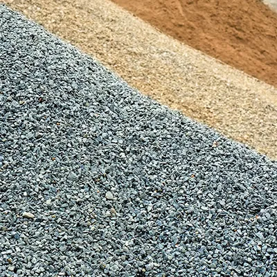 A red fire hydrant sitting on top of a pile of gravel.